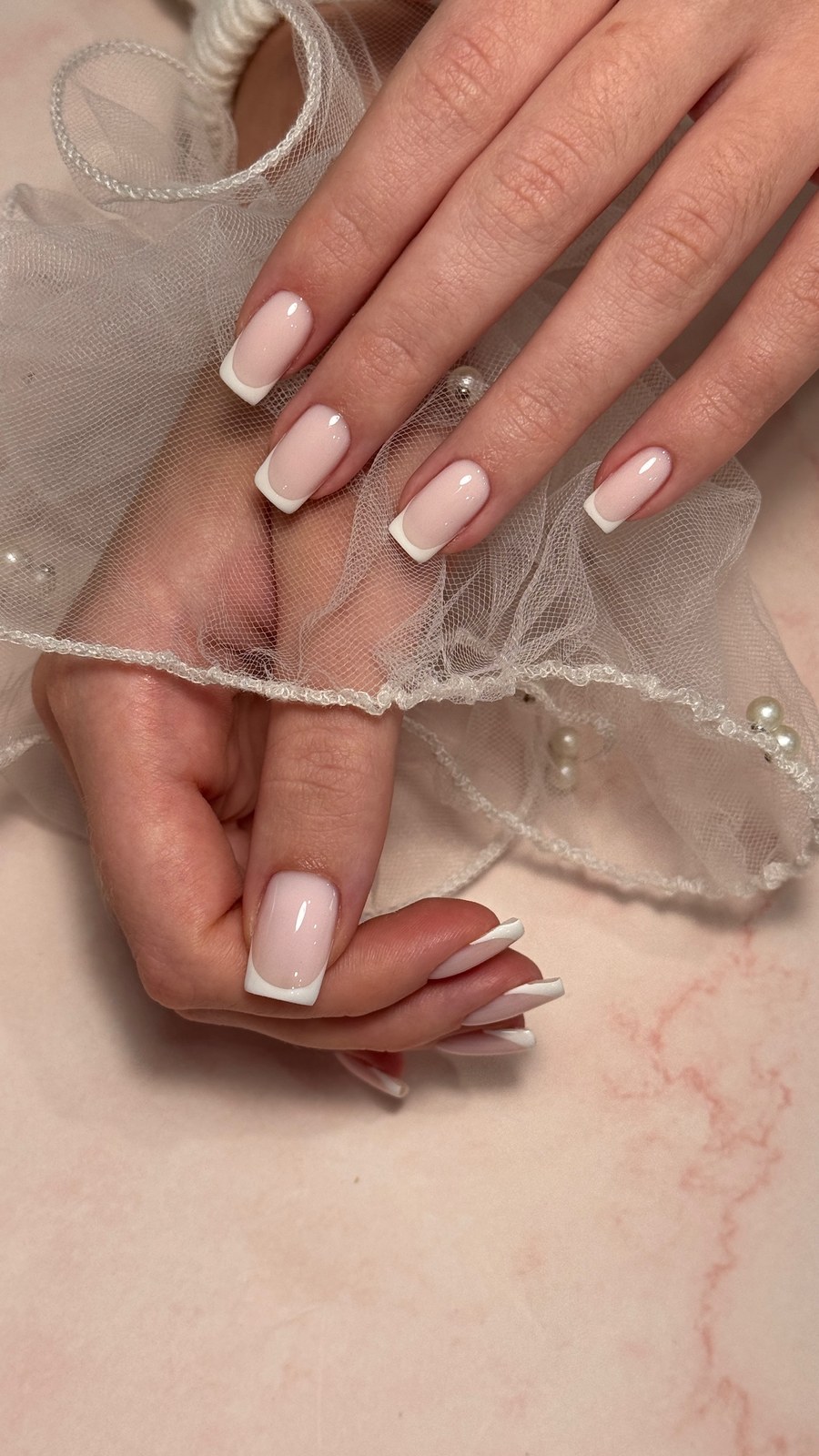 Nude and white manicure styled with pearls and lace