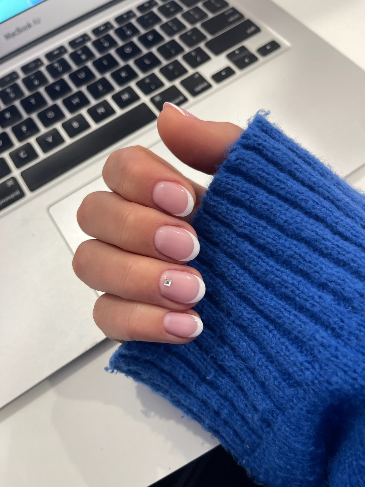 Nude glossy manicure resting on laptop