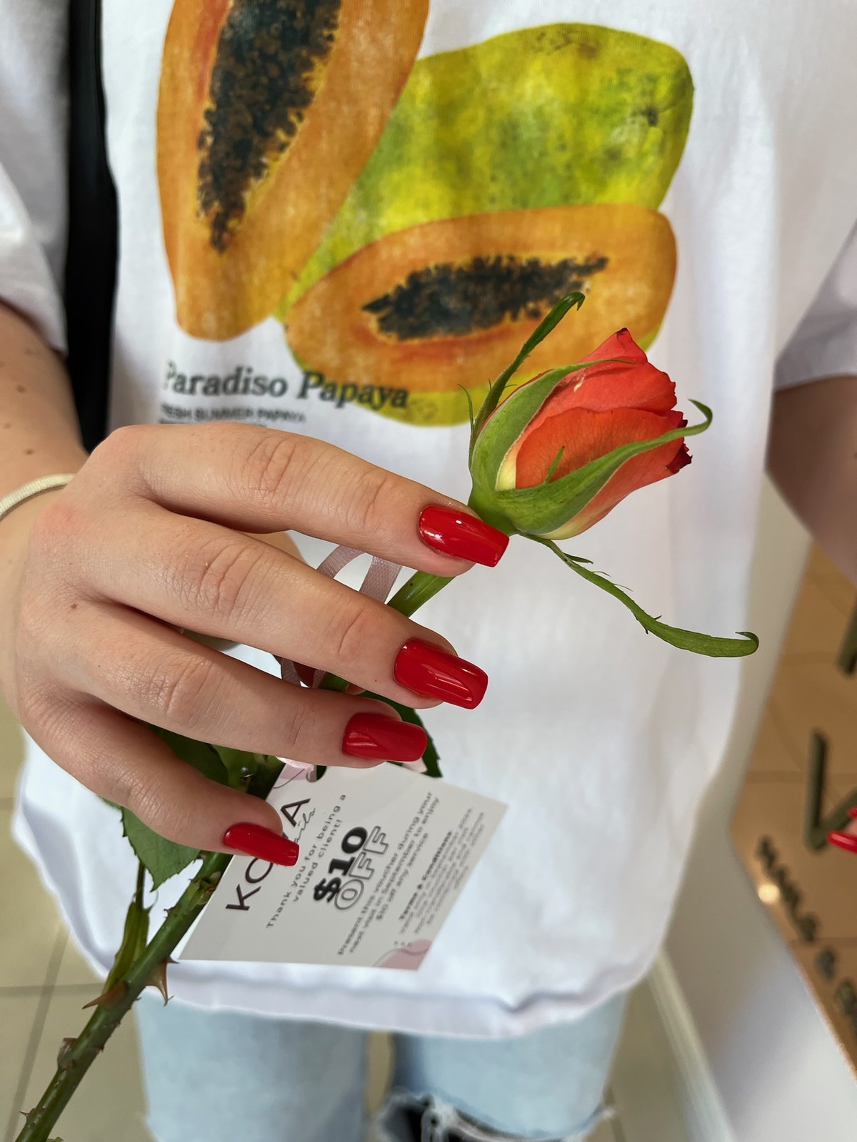Classic red glossy manicure holding a rose
