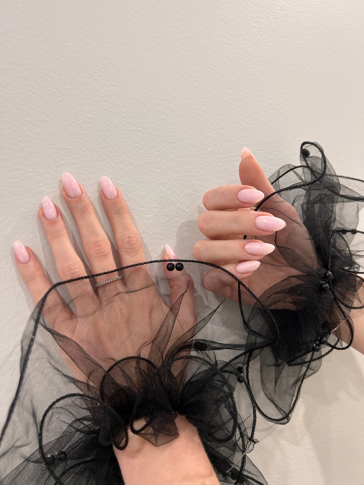 Pale pink glossy manicure styled with black lace