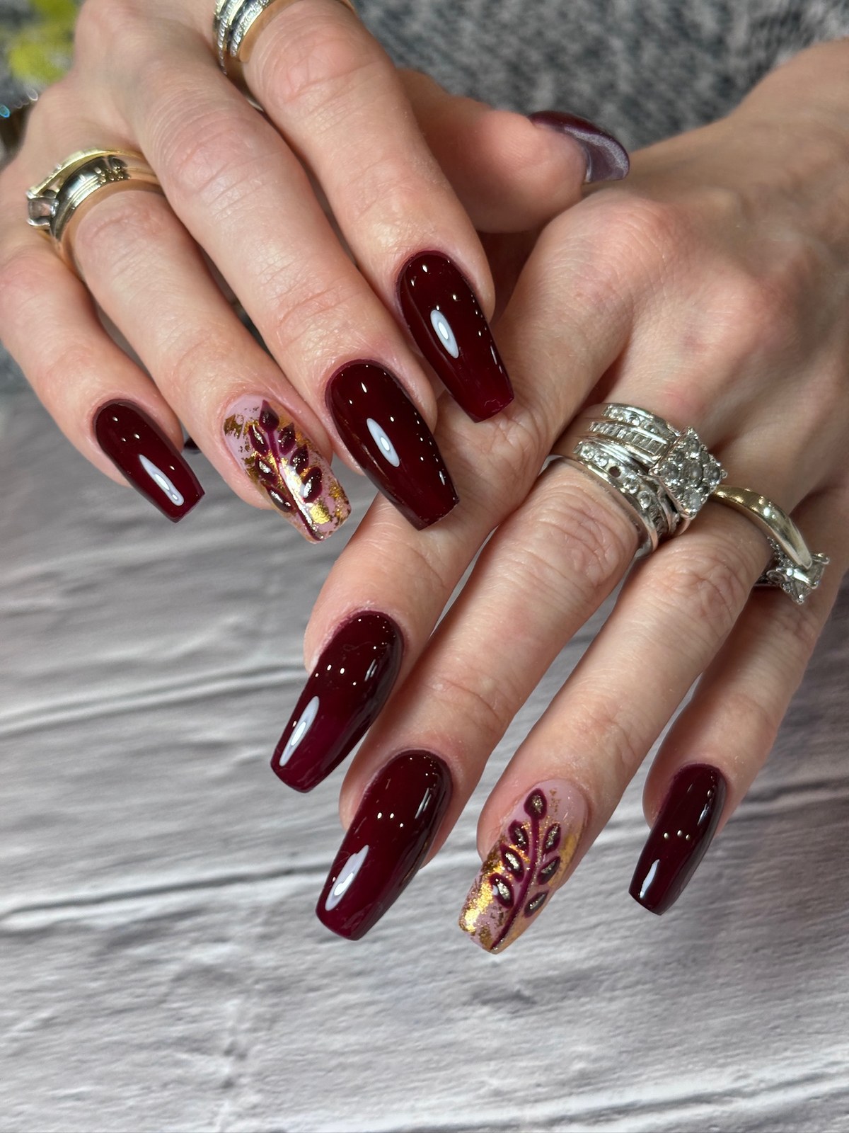 Burgundy nails with gold leaf nail art accent