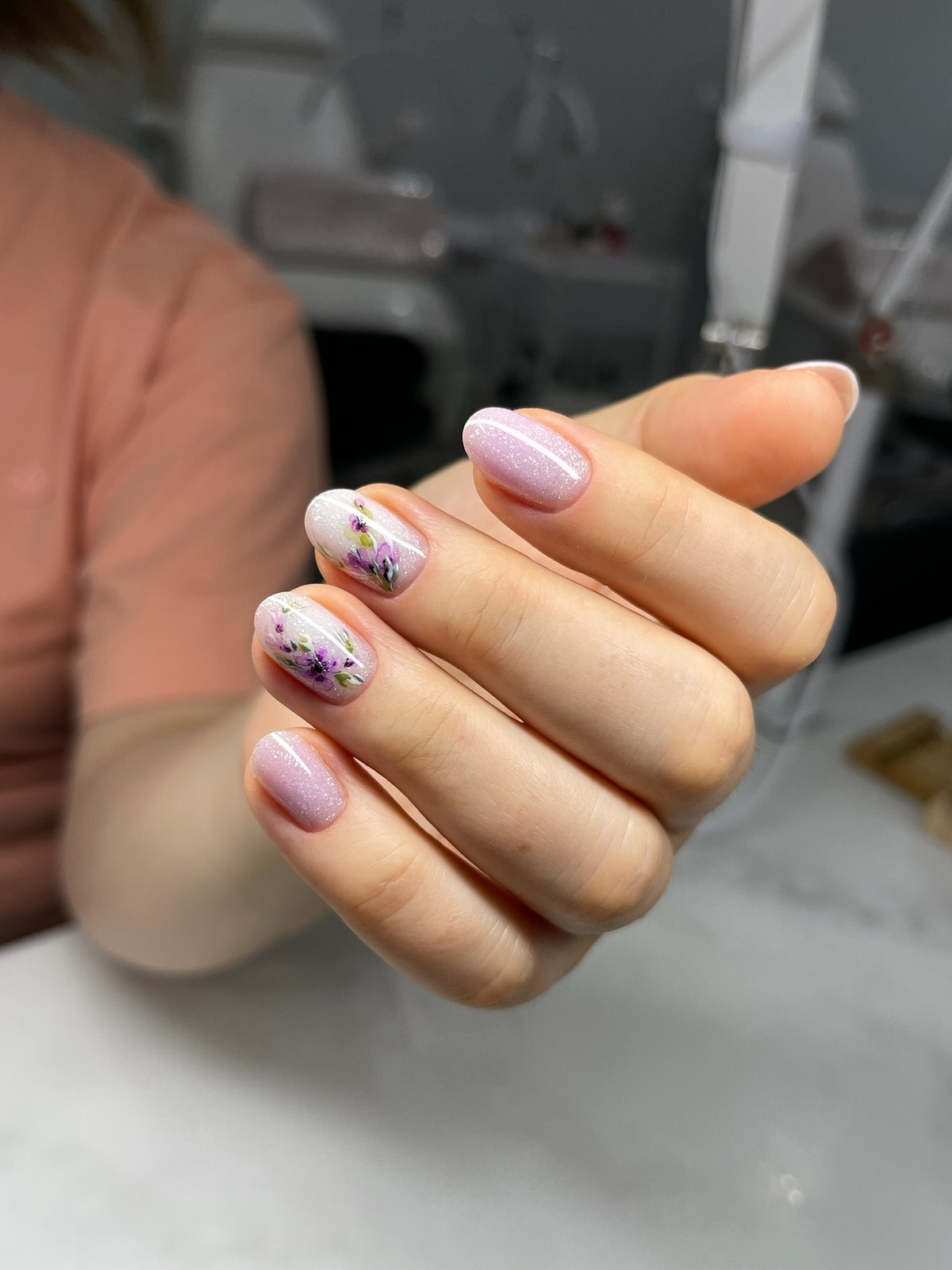 Hand-painted purple flower nail art on glitter lilac base